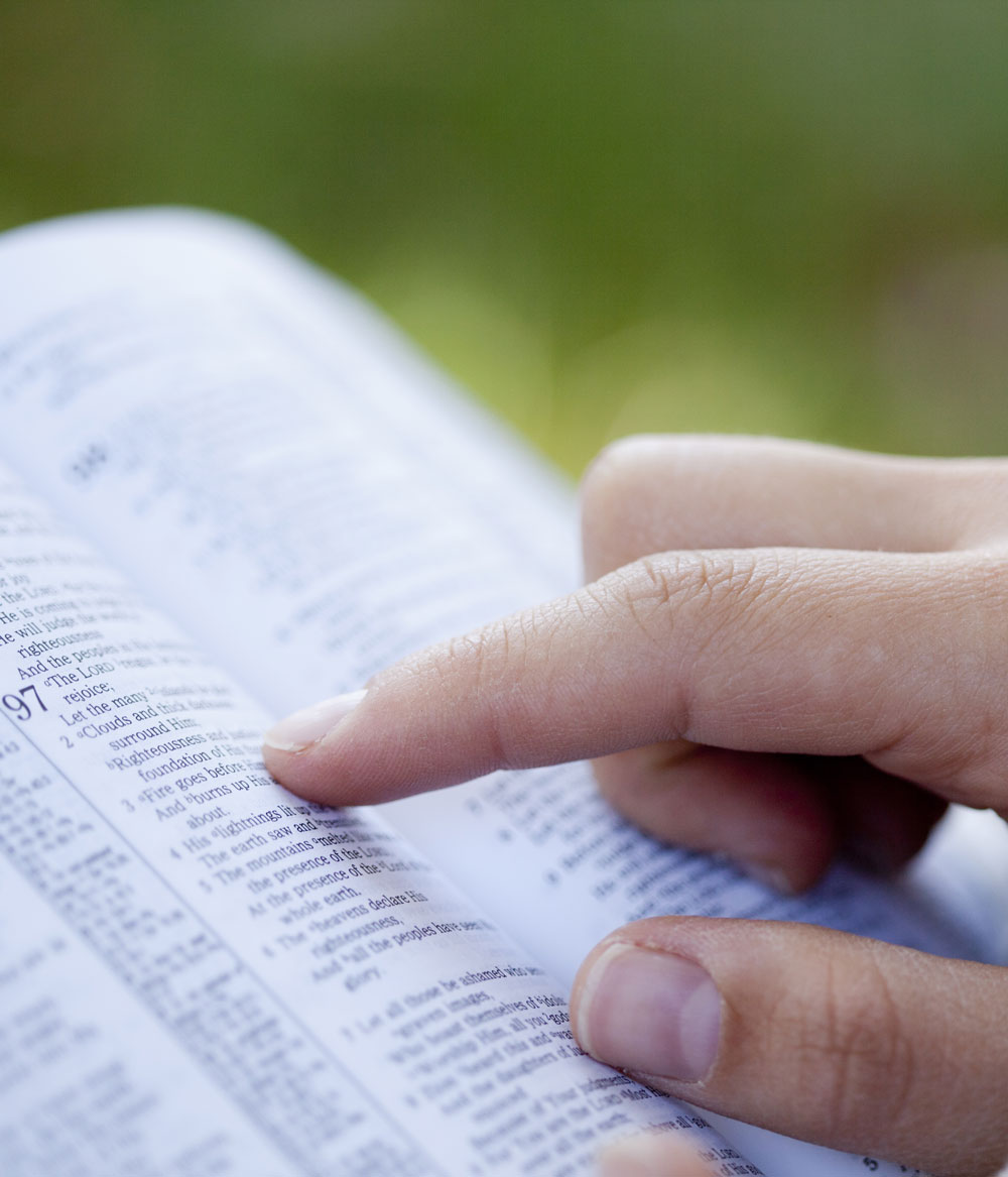 close-up of someone pointing to verses in a bible