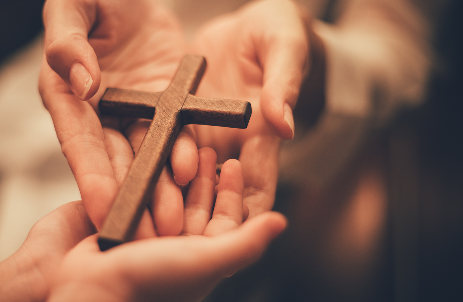 two hands holding a small cross