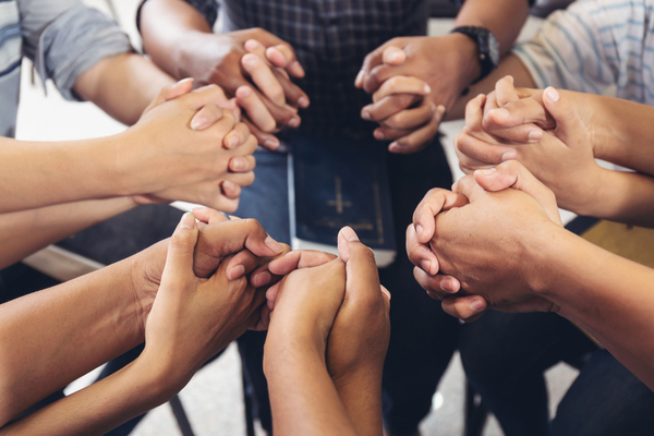 A group of new church friends hold hands.