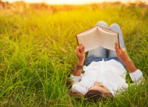 woman laying outside reading on the grass