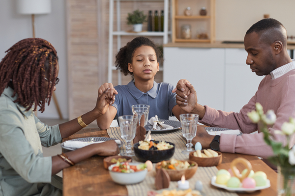 A family prays together at the dinner table.