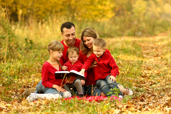 A family sits in the grass reading the Bible together.