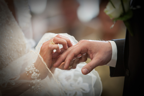 A bride puts a wedding ring om her groom's finger.