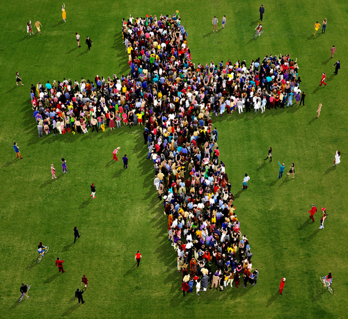 A large crowd of people gather in the shape of a cross.