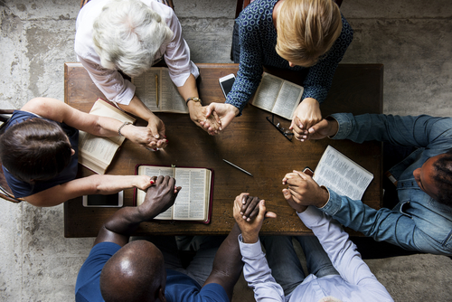 Aerial view of a Bible study class holding hands.