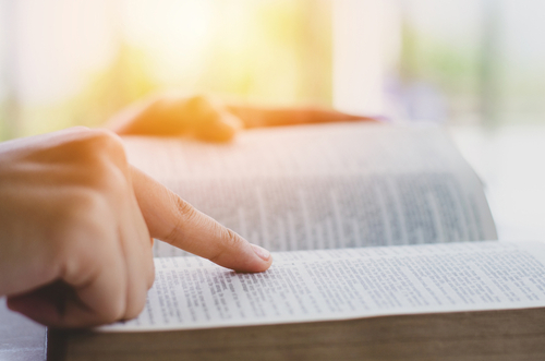 A woman reads a Bible and points to her favorite verse.