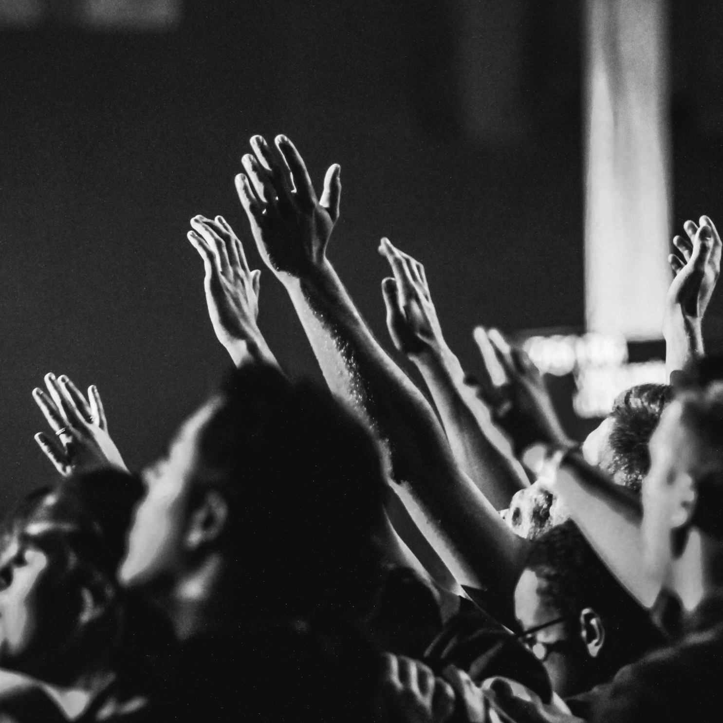 black and white image of hands in the air worshipping