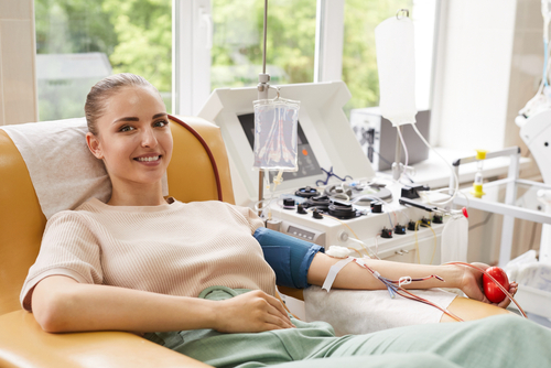 A young woman reclines as she donates blood.