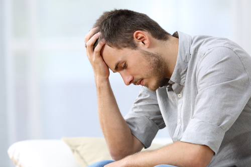 A distraught young man sits on his couch.