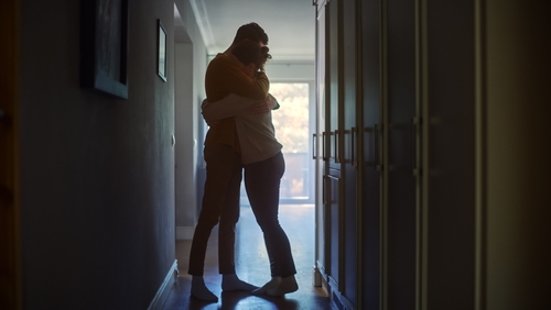 A couple embraces in a corridor.