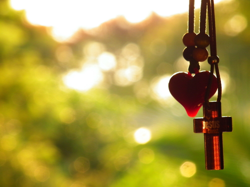 Necklace with a cross hanging next to a heart.