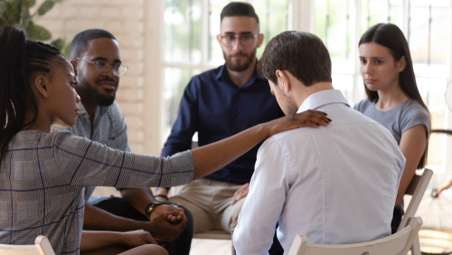 Members consult a man in a grief support group.