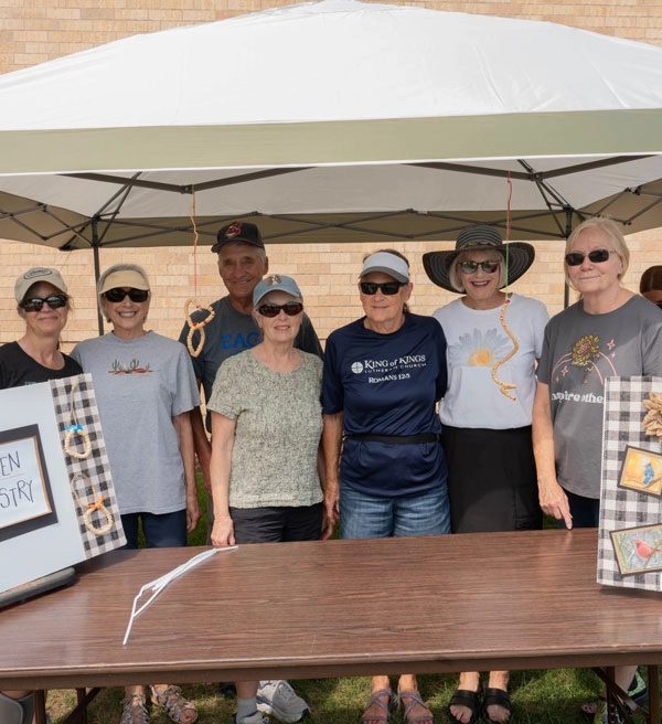 Group standing under a tent outside waiting for people to register for an event
