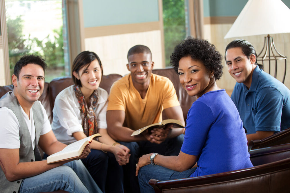 A group of adults in a Bible study group smiles at the camera.