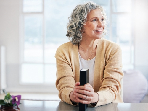 An older woman smiles while holding a Bible
